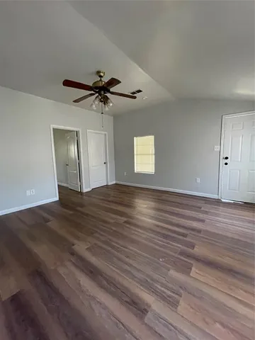 a view of empty room with wooden floor and fan