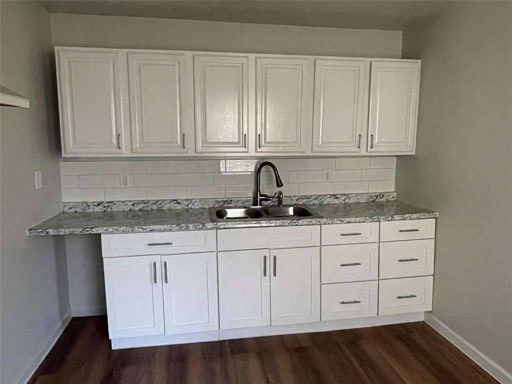 1041 Bradfield Road Dallas, TX 75217 - Photo 7 of 9 a kitchen with granite countertop white cabinets and sink