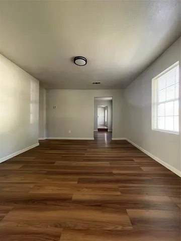 a view of empty room with window and wooden floor