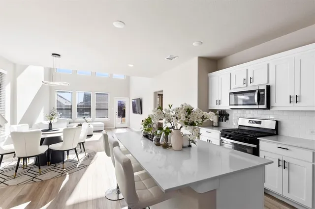 a kitchen with stainless steel appliances kitchen island granite countertop a stove a sink a dining table and chairs with wooden floor