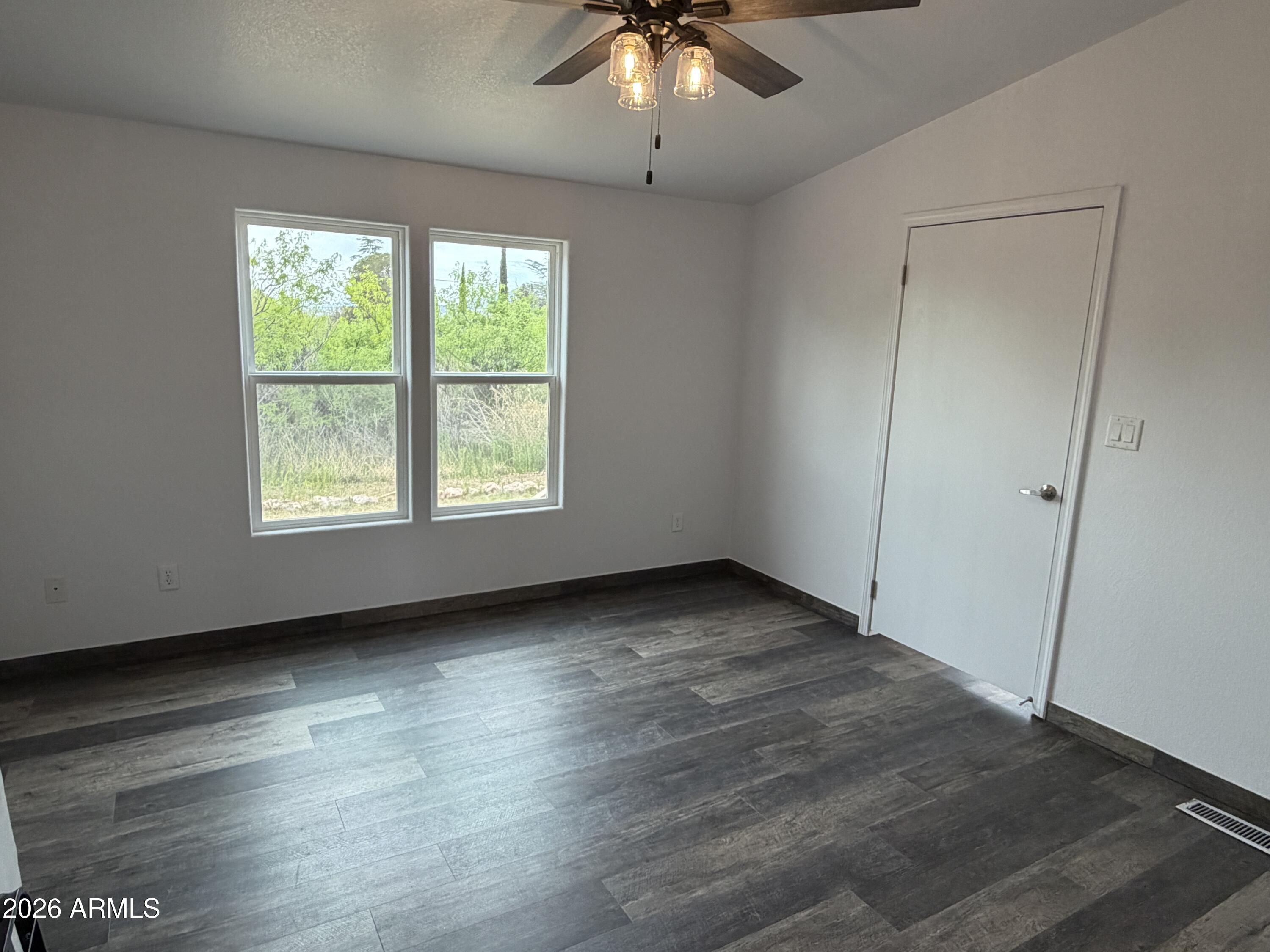 928 West Austin Street Bisbee, AZ 85603 - Photo 12 of 27 an empty room with wooden floor chandelier fan and windows