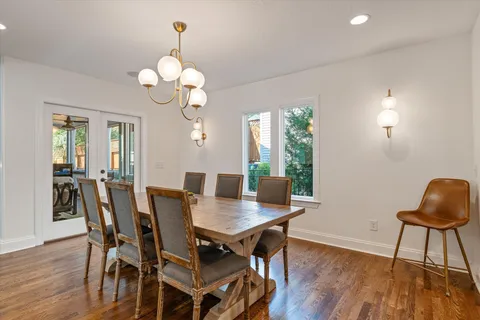 a kitchen with stainless steel appliances granite countertop a sink a stove a dining table and chairs with wooden floor