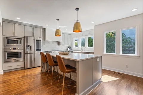 a large kitchen with stainless steel appliances granite countertop a stove and a wooden floors