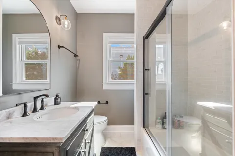 a bedroom with a bed a computer on table and a large window