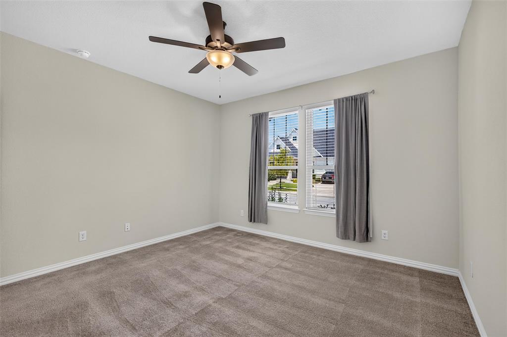 8715 Royal Star Road Rowlett, TX 75089 - Photo 7 of 39 Ceiling fan with integrated lighting, two windows with blinds, light-toned wall paint, and gray carpeting
