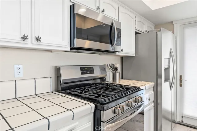 a kitchen with stainless steel appliances kitchen island granite countertop a sink and white cabinets