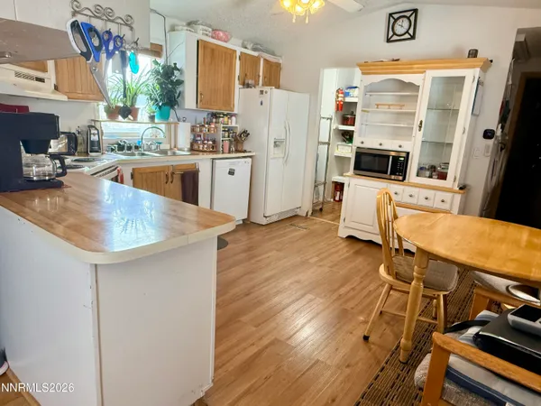 a kitchen with stainless steel appliances a stove a refrigerator a dining table and chairs with wooden floor