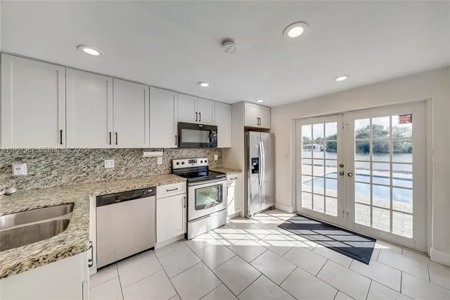 a kitchen with granite countertop a stove a sink and a refrigerator