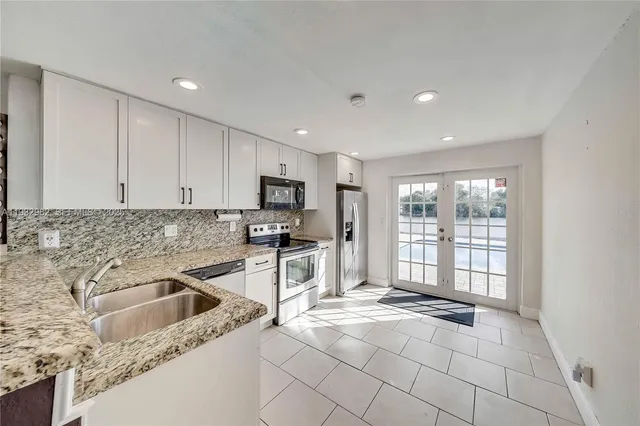 a kitchen with granite countertop a stove a sink and a refrigerator