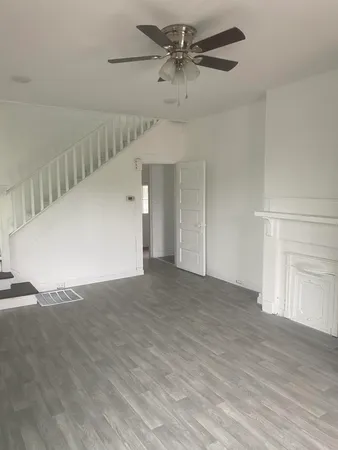 a view of a big room with carpet and a chandelier fan