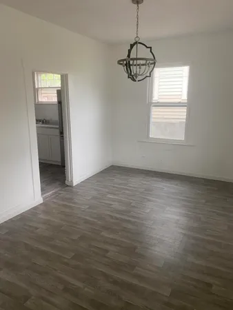 an empty room with wooden floor cabinet and windows