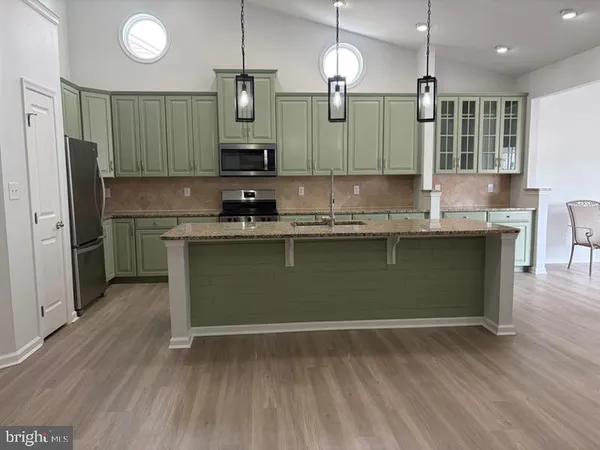 a kitchen with kitchen island granite countertop a sink cabinets and stainless steel appliances