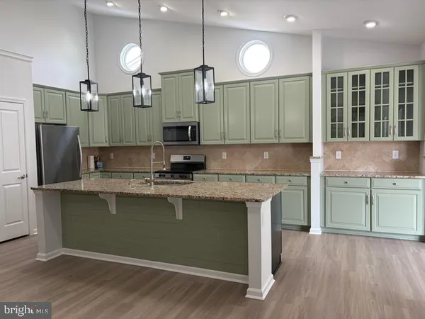 a kitchen with kitchen island granite countertop a sink cabinets and stainless steel appliances