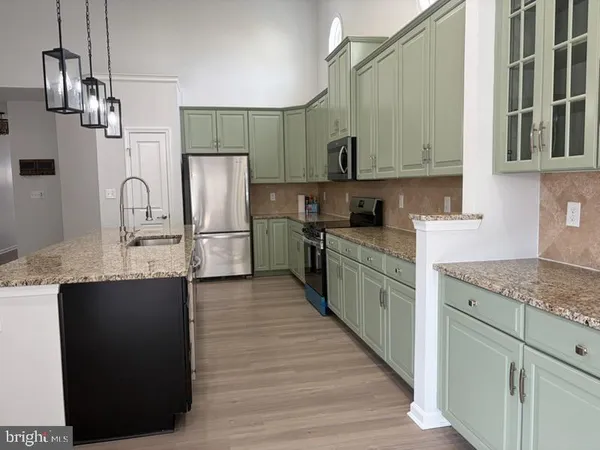 a kitchen with stainless steel appliances granite countertop a sink refrigerator and cabinets