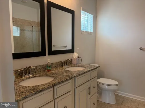a bathroom with a granite countertop toilet a sink and a mirror