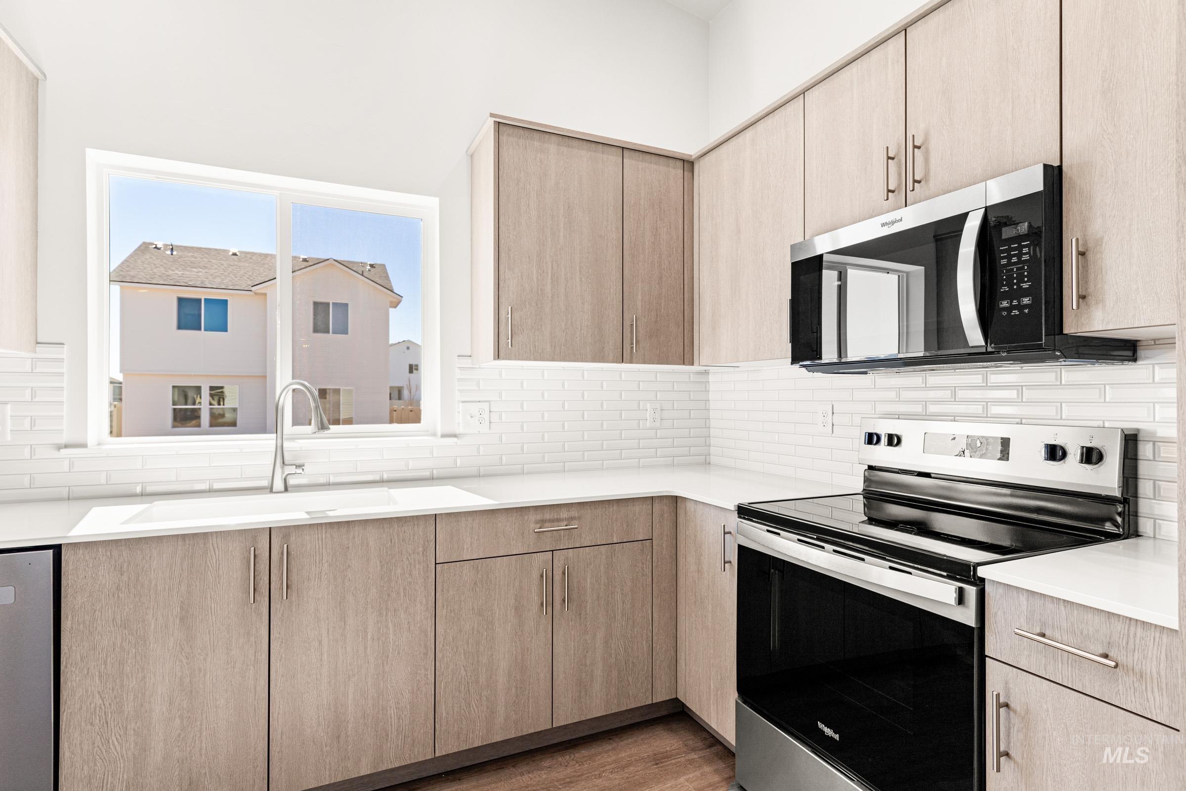 1077 West Jasper Street Meridian, ID 83642 - Photo 5 of 19 Modern kitchen featuring wood-finish cabinetry, white subway tile backsplash, and light-toned countertops