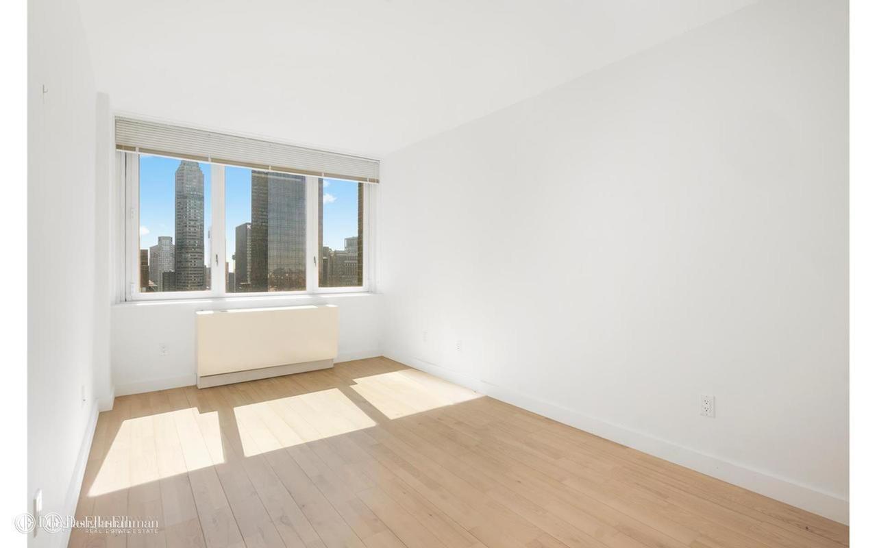 322 West 57th Street, Unit 55S1 Manhattan, NY 10019 - Photo 21 of 33 a view of an empty room with wooden floor and a window