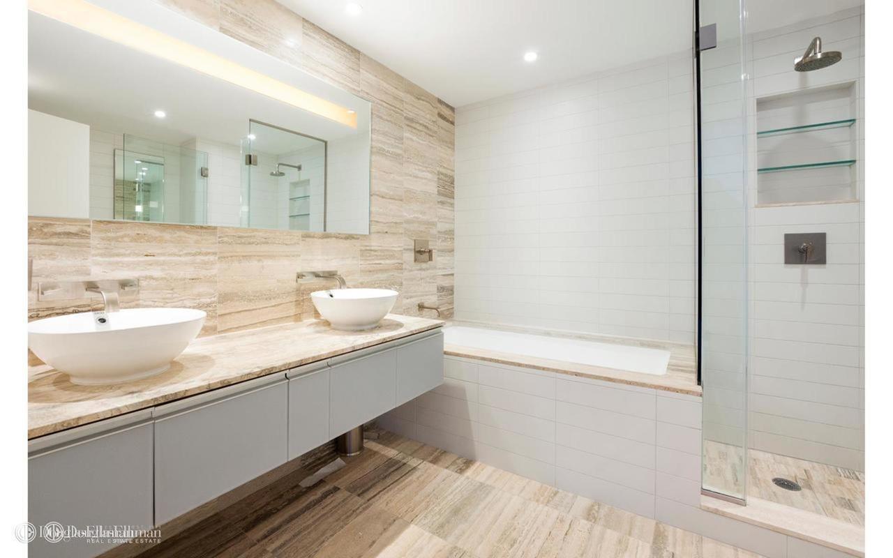 322 West 57th Street, Unit 55S1 Manhattan, NY 10019 - Photo 24 of 33 a bathroom with a double vanity sink a mirror and a shower