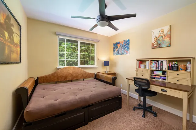 a bedroom with a bed a computer on a desk and a book shelf