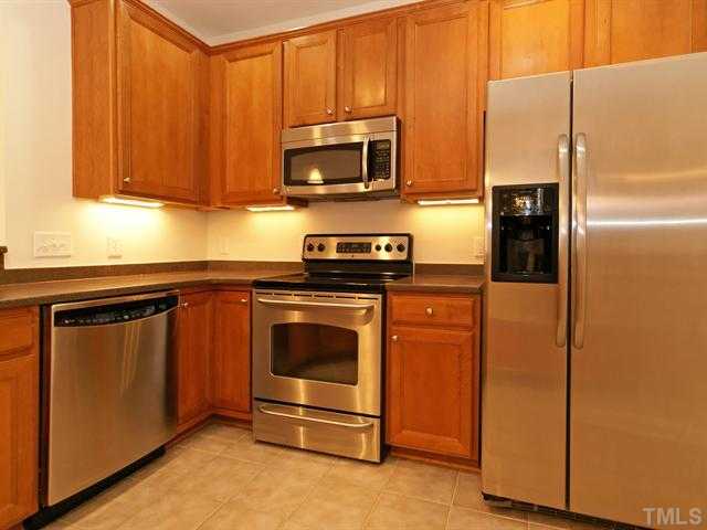 7122 Racine Way Raleigh, NC 27615 - Photo 3 of 20 Cooking is a delight in the kitchen that hosts stainless steel appliances, cabinets with crown and under-cabinet lights, Corian counters, and tile floors.