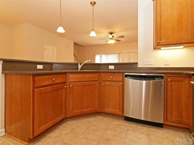 7122 Racine Way Raleigh, NC 27615 - Photo 4 of 20 Cooking is a delight in the kitchen that hosts stainless steel appliances, cabinets with crown and under-cabinet lights, Corian counters, and tile floors.