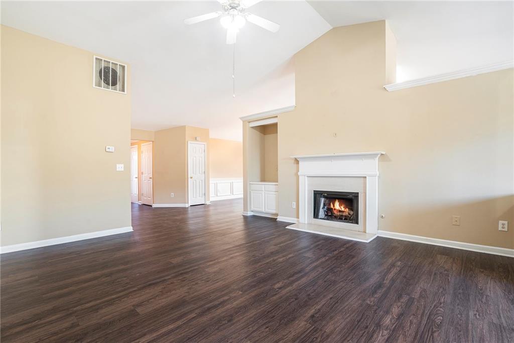 a view of an empty room with wooden floor fireplace and a window