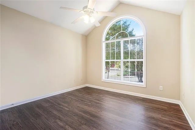 an empty room with wooden floor windows and fan