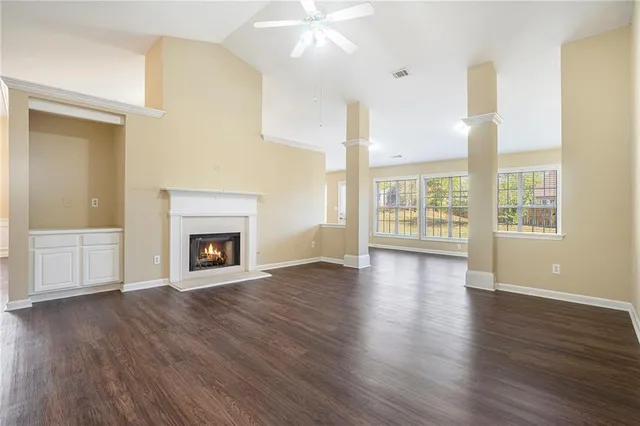 an empty room with wooden floor fireplace and windows