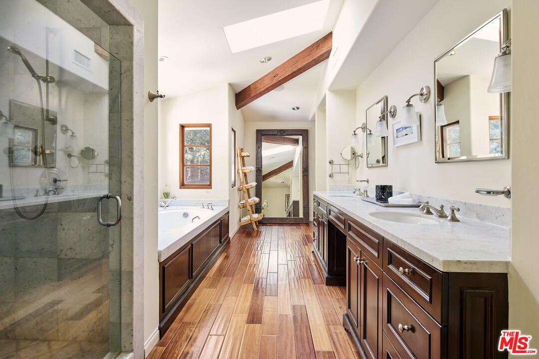 3268 Serra Road Malibu, CA 90265 - Photo 11 of 24 a bathroom with a granite countertop double vanity sink a mirror and a shower
