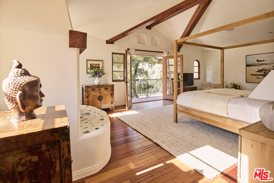 3268 Serra Road Malibu, CA 90265 - Photo 10 of 24 a bedroom with a bed and wooden floor