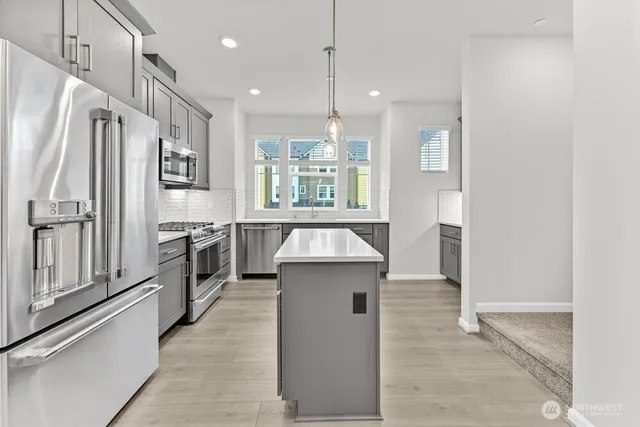 a kitchen with stainless steel appliances granite countertop a refrigerator a sink and a stove