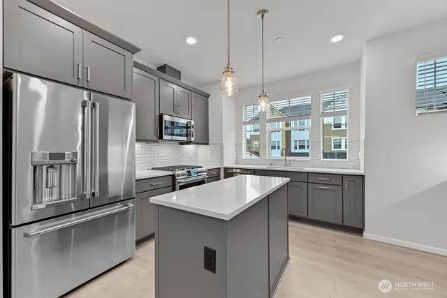 a kitchen with kitchen island granite countertop a sink refrigerator and microwave