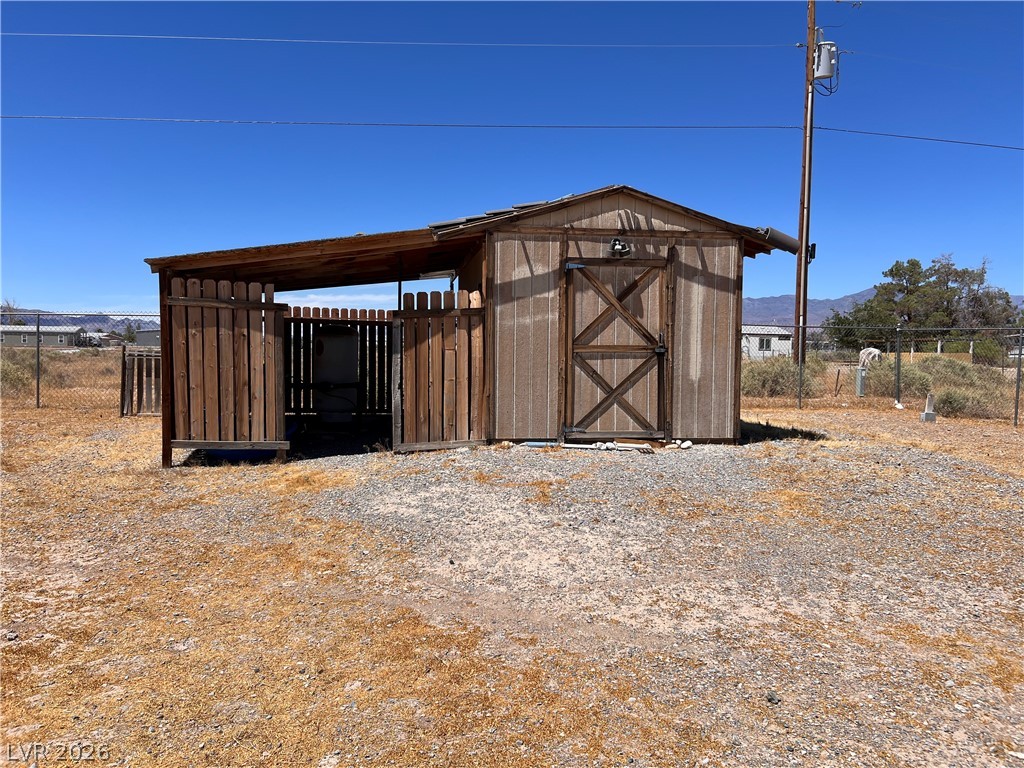 200 East Gamebird Road Pahrump, NV 89048 - Photo 22 of 23 A rustic storage shed with a lean-to overhang offers practical outdoor utility in a vast landscape.