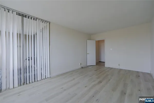 a view of an empty room with glass door and wooden floor