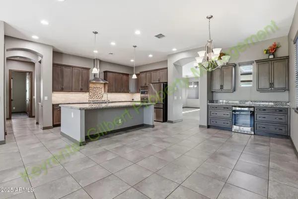 a kitchen with kitchen island granite countertop a refrigerator and a sink