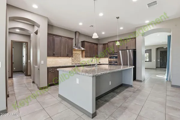 a large kitchen with stainless steel appliances kitchen island granite countertop a stove a sink a counter top space and cabinets