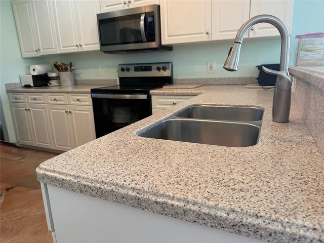 a kitchen with stainless steel appliances granite countertop a sink a stove and a microwave