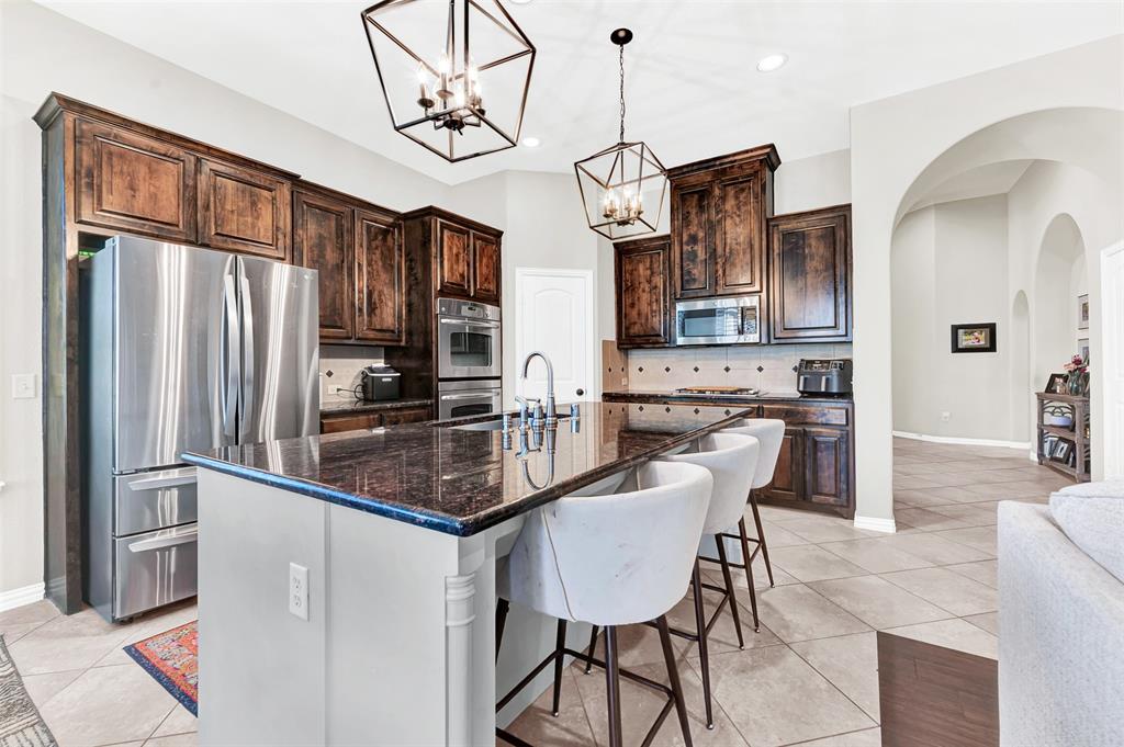 10104 Gentry Drive Frisco, TX 75035 - Photo 8 of 39 a kitchen with stainless steel appliances granite countertop a refrigerator a stove a sink a dining table and chairs with wooden floor