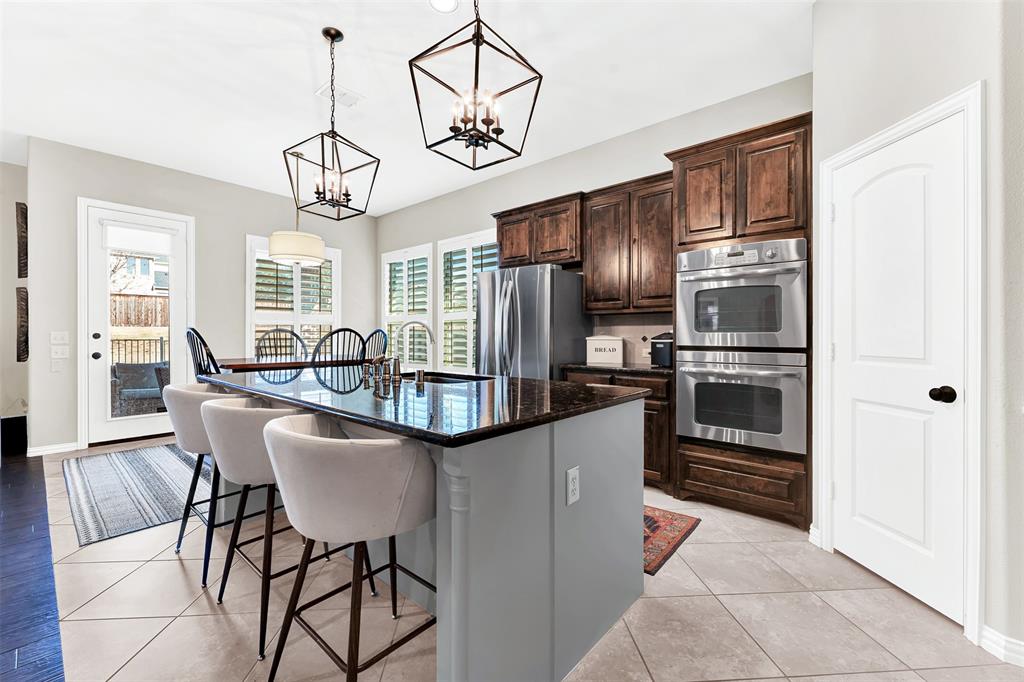 10104 Gentry Drive Frisco, TX 75035 - Photo 9 of 39 a kitchen with stainless steel appliances granite countertop a refrigerator a stove and a sink with wooden floor