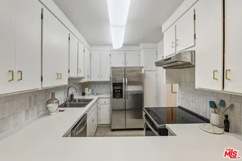 a kitchen with stainless steel appliances granite countertop a sink refrigerator and cabinets
