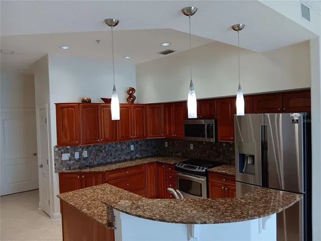 a kitchen with granite countertop a sink a counter space appliances and cabinets