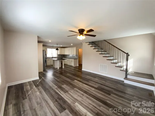 a view of a livingroom with wooden floor and a kitchen