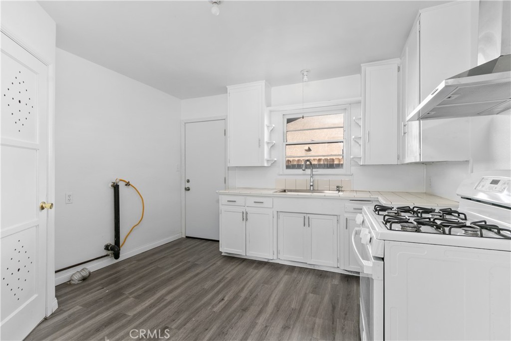 735 Michigan Avenue Beaumont, CA 92223 - Photo 4 of 19 a kitchen with granite countertop a stove a sink dishwasher and white cabinets with wooden floor