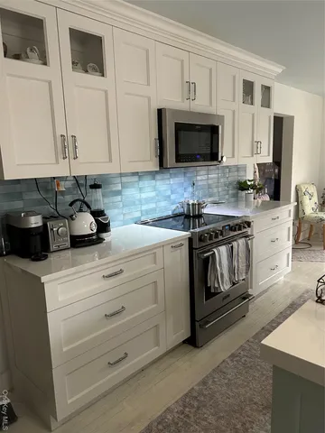 a kitchen with white cabinets and black appliances
