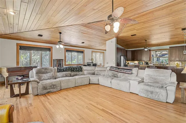 a living room with couches and kitchen view with wooden floor