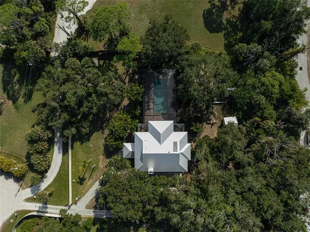 an aerial view of residential house with parking and trees