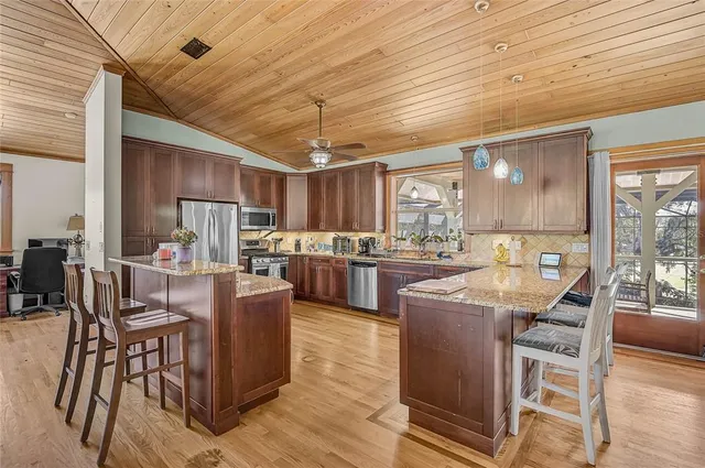 a kitchen with stainless steel appliances kitchen island granite countertop a table chairs stove and white cabinets