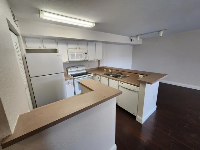 a kitchen with a refrigerator stove and wooden floor