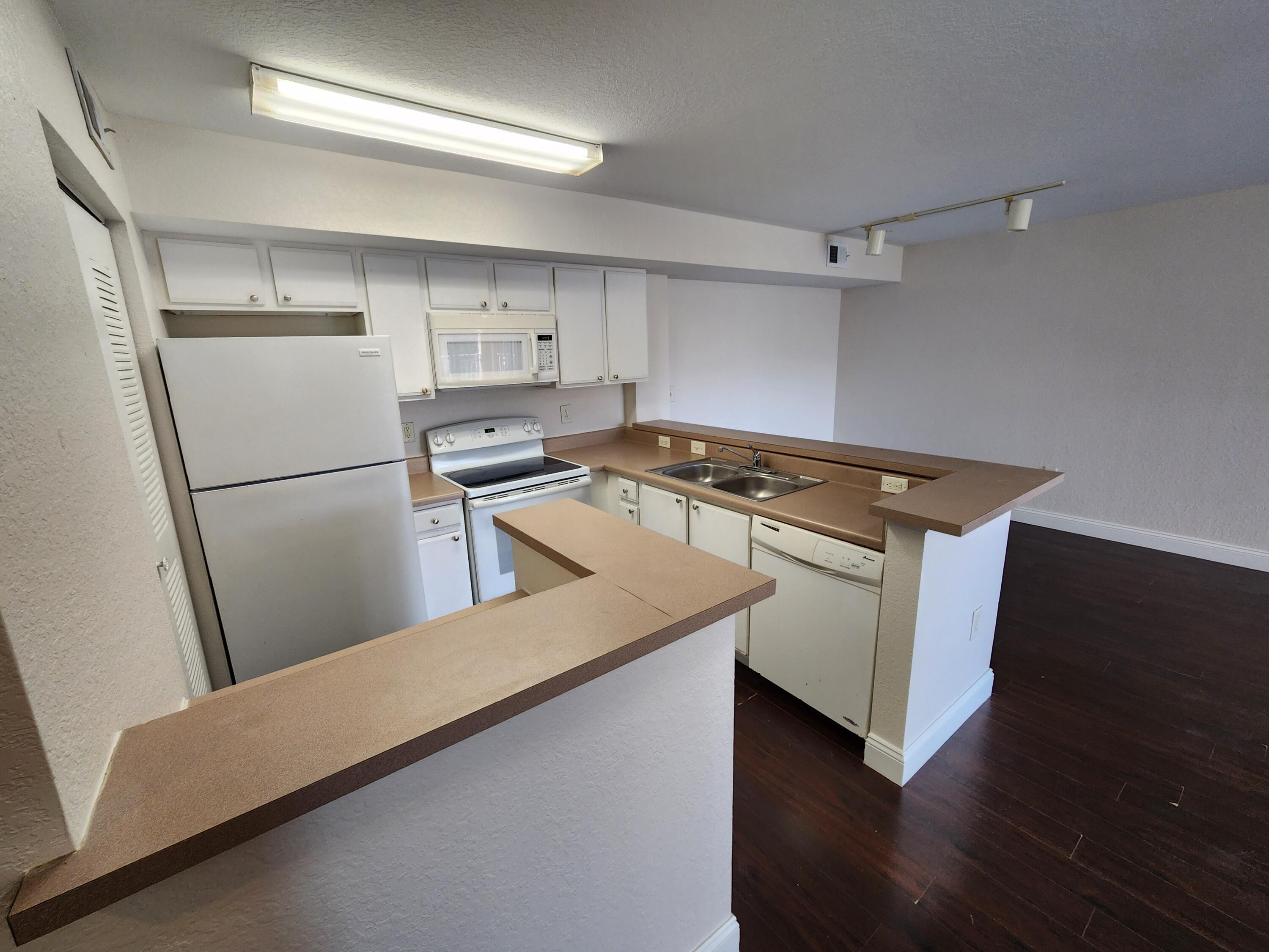 161 Southwest Palm Drive, Unit 205 Port St. Lucie, FL 34986 - Photo 22 of 22 a kitchen with a refrigerator stove and wooden floor