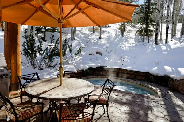 a backyard of a house with table and chairs under an umbrella